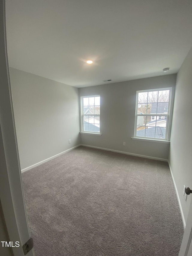 carpeted spare room featuring baseboards