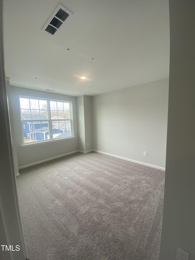 carpeted spare room with visible vents and baseboards