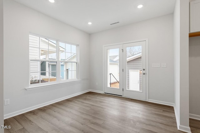 interior space featuring plenty of natural light, wood finished floors, visible vents, and baseboards