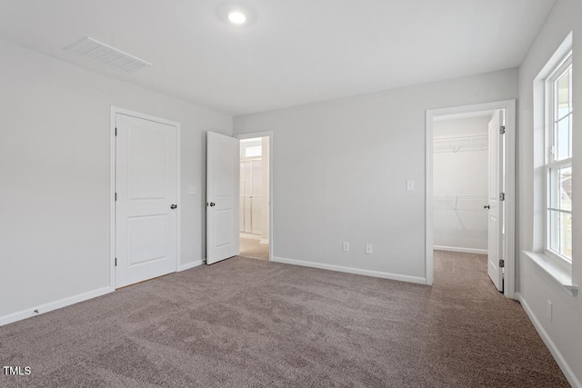 unfurnished bedroom with carpet, multiple windows, visible vents, and baseboards