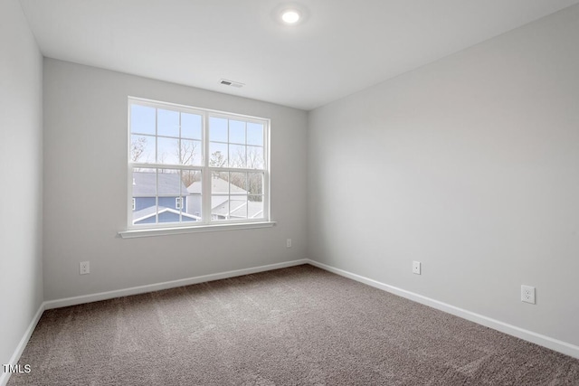 empty room featuring carpet, visible vents, and baseboards