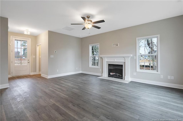 unfurnished living room featuring a wealth of natural light and dark wood-type flooring