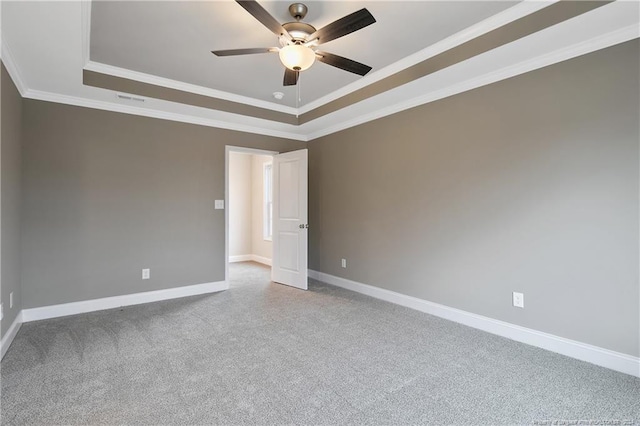 carpeted empty room featuring a raised ceiling, ceiling fan, and crown molding