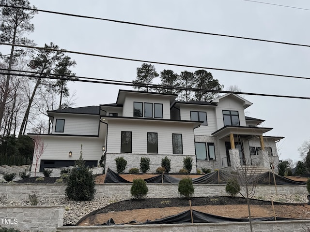 view of front of home with stone siding and a balcony