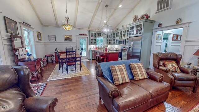 living room with an inviting chandelier, hardwood / wood-style flooring, and high vaulted ceiling