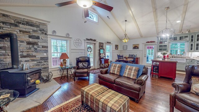 living room with a wood stove, a healthy amount of sunlight, ceiling fan, and dark wood-type flooring