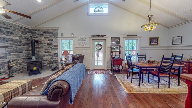 dining room featuring dark wood-type flooring, a wood stove, high vaulted ceiling, and ceiling fan