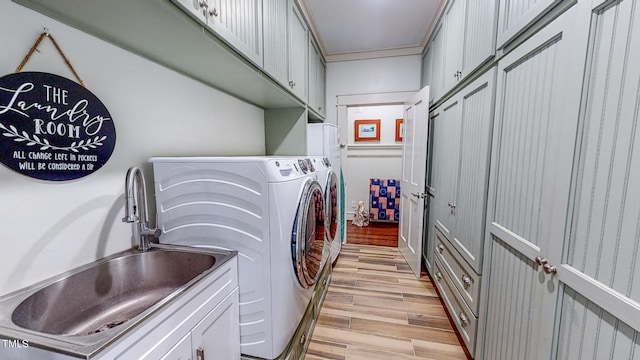 laundry room with light hardwood / wood-style floors, sink, cabinets, and independent washer and dryer