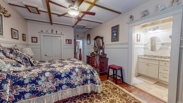 bedroom featuring light hardwood / wood-style flooring, ensuite bath, sink, ceiling fan, and coffered ceiling