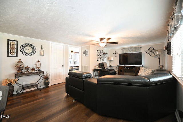 living room featuring dark hardwood / wood-style flooring, ceiling fan, ornamental molding, and a textured ceiling