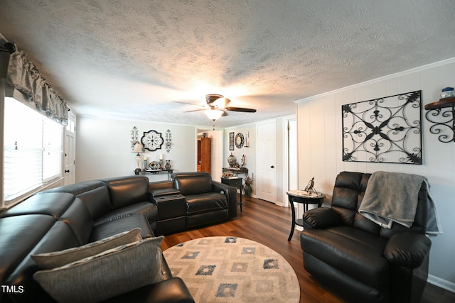 living room with ceiling fan, dark wood-type flooring, ornamental molding, and a textured ceiling