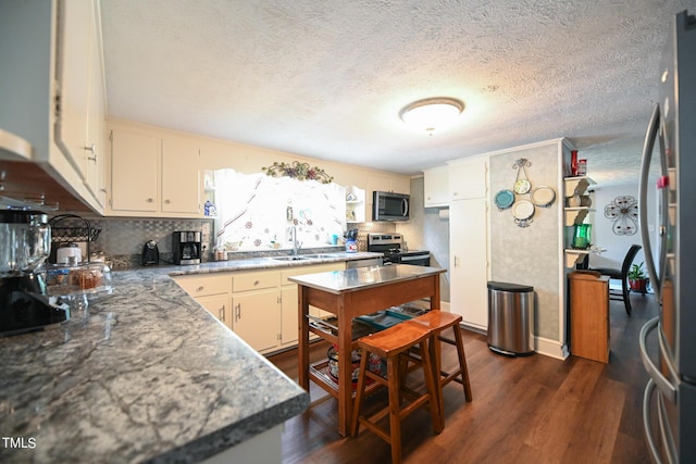 kitchen featuring sink, a textured ceiling, appliances with stainless steel finishes, dark hardwood / wood-style floors, and decorative backsplash