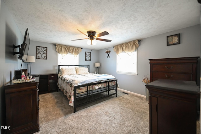 carpeted bedroom with multiple windows, ceiling fan, and a textured ceiling