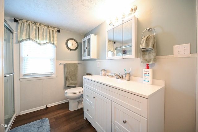 bathroom with a shower with door, vanity, wood-type flooring, a textured ceiling, and toilet