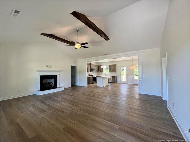 unfurnished living room with dark wood-type flooring, beamed ceiling, high vaulted ceiling, and ceiling fan