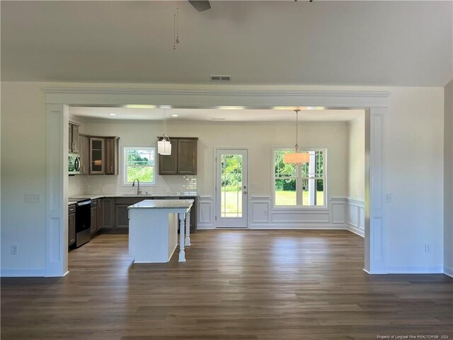 kitchen featuring appliances with stainless steel finishes, decorative light fixtures, a center island, and sink