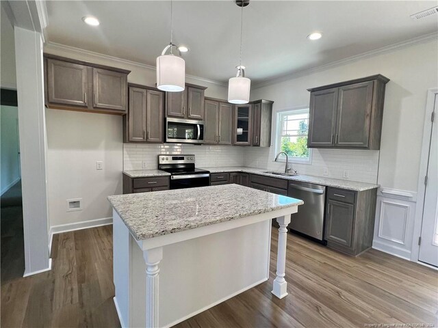 kitchen with backsplash, appliances with stainless steel finishes, a center island, dark wood-type flooring, and sink