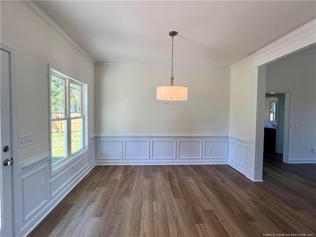 unfurnished dining area featuring dark wood-type flooring, ornamental molding, and wainscoting