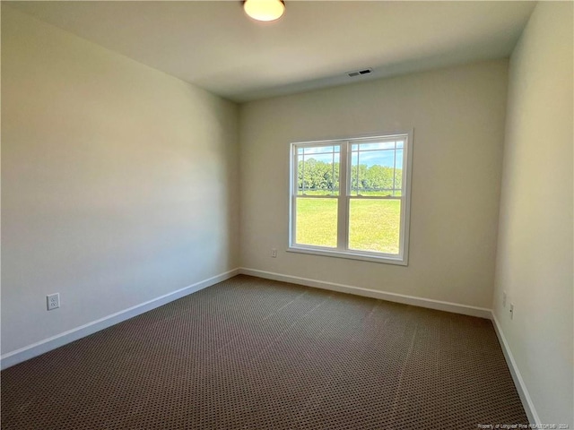 unfurnished room with dark colored carpet, visible vents, and baseboards