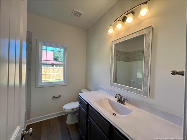 bathroom featuring vanity, wood finished floors, visible vents, baseboards, and toilet