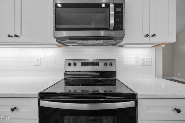 kitchen with white cabinetry, appliances with stainless steel finishes, light stone counters, and backsplash