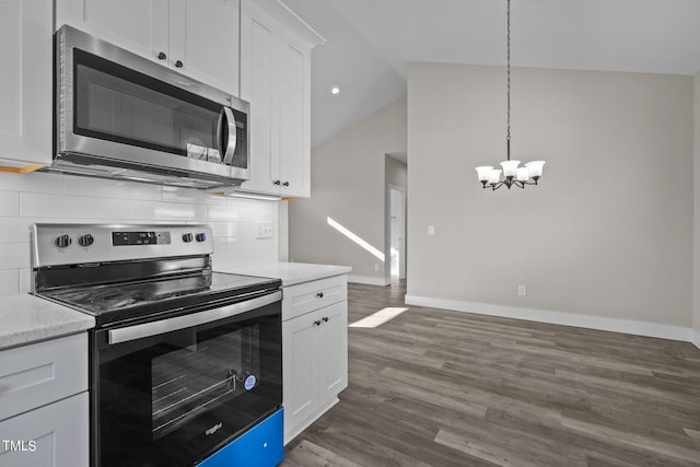 kitchen with vaulted ceiling, appliances with stainless steel finishes, white cabinets, hanging light fixtures, and dark wood-type flooring