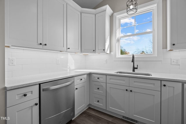 kitchen featuring dark wood-type flooring, sink, white cabinetry, stainless steel dishwasher, and light stone countertops