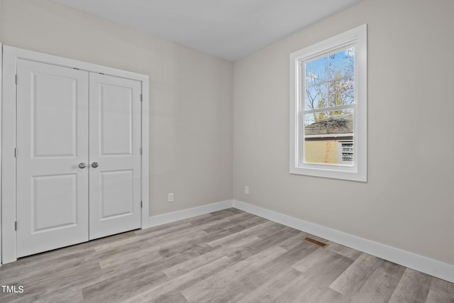 unfurnished bedroom with a closet and light wood-type flooring