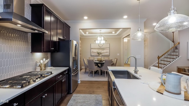 kitchen featuring sink, wall chimney exhaust hood, tasteful backsplash, pendant lighting, and appliances with stainless steel finishes