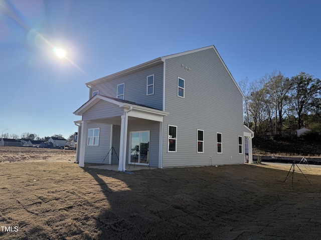 back of property with a lawn and a patio