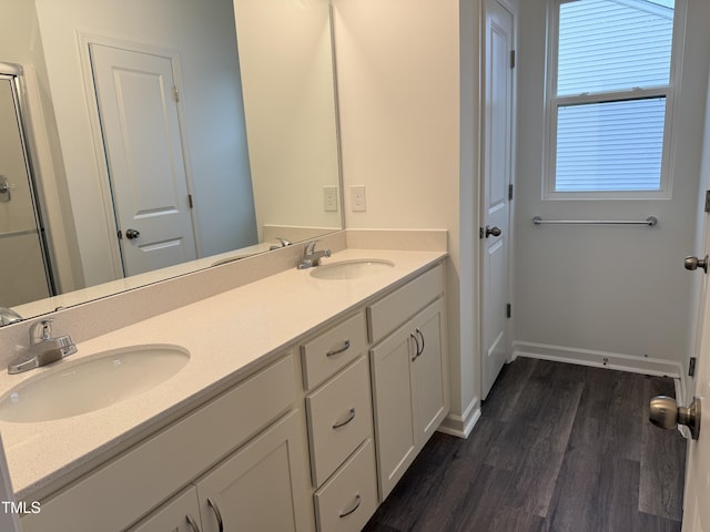 full bathroom with double vanity, wood finished floors, a sink, and baseboards