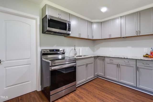 kitchen with dark wood-type flooring, light stone counters, appliances with stainless steel finishes, and sink