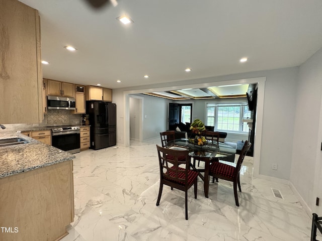 kitchen featuring tasteful backsplash, light tile patterned floors, light stone counters, appliances with stainless steel finishes, and sink