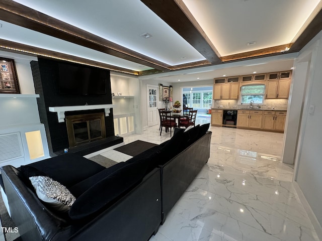 tiled living room with sink, a fireplace, beam ceiling, a tray ceiling, and wine cooler