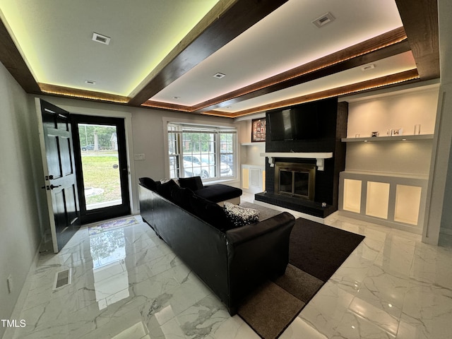 living room with a large fireplace, light tile patterned flooring, built in features, and a tray ceiling