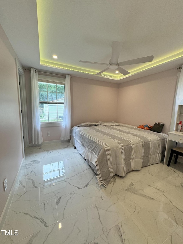 bedroom featuring ceiling fan, tile patterned flooring, and a tray ceiling