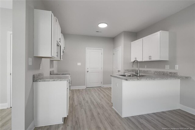 57 E Third St, Parkton, NC 28371 - kitchen featuring light wood-style flooring, a peninsula, and white cabinets