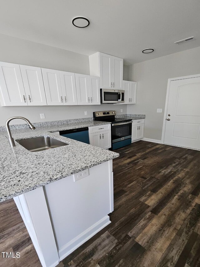 kitchen with white cabinetry, sink, light stone counters, appliances with stainless steel finishes, and dark wood-type flooring