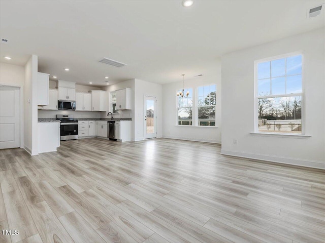 unfurnished living room featuring a chandelier and light hardwood / wood-style flooring