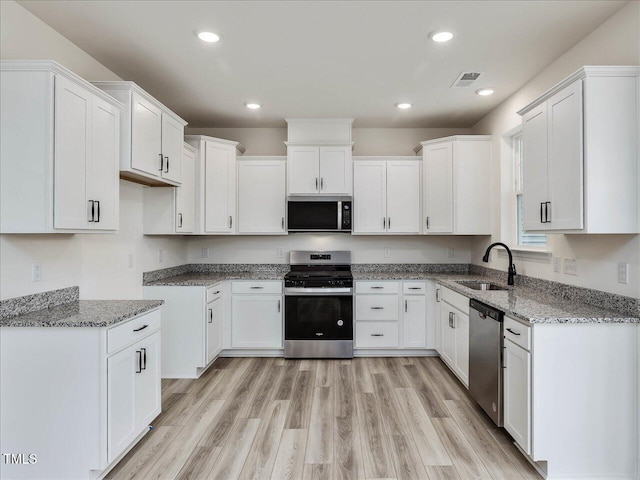 kitchen featuring sink, light wood-type flooring, light stone countertops, stainless steel appliances, and white cabinets