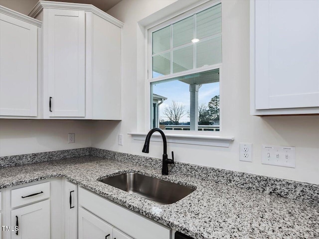 kitchen featuring white cabinets, sink, and light stone counters