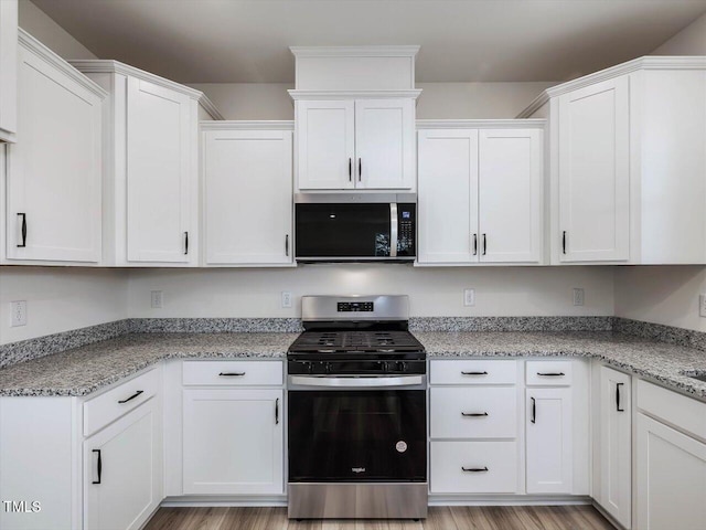 kitchen featuring light hardwood / wood-style floors, light stone counters, stainless steel appliances, and white cabinetry