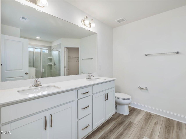 bathroom with a shower with shower door, hardwood / wood-style floors, toilet, and vanity