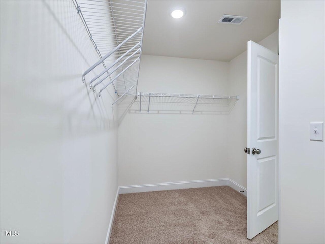 walk in closet featuring light colored carpet