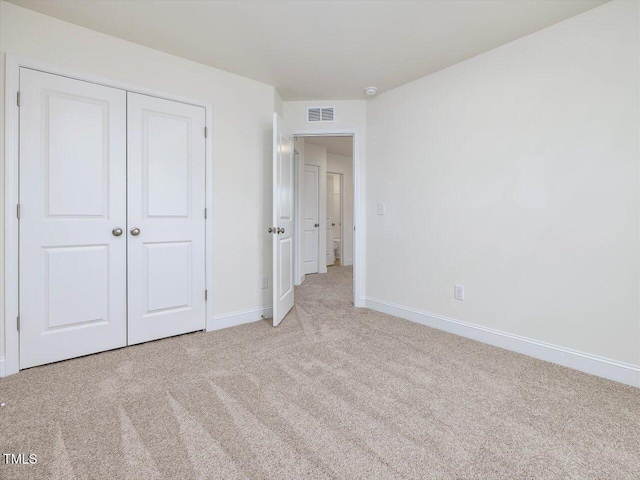 unfurnished bedroom with light carpet and a closet