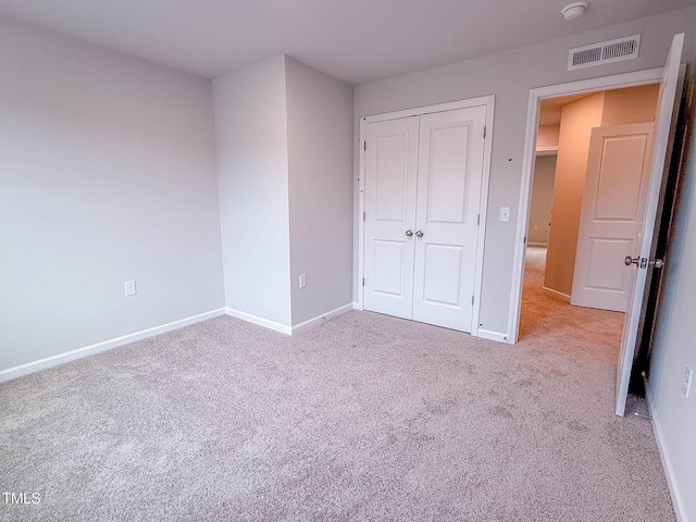 unfurnished bedroom featuring light carpet and a closet