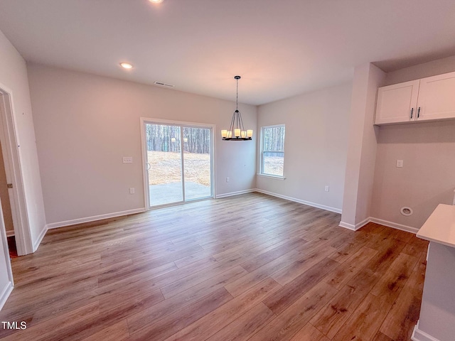 unfurnished dining area featuring light hardwood / wood-style floors and a notable chandelier