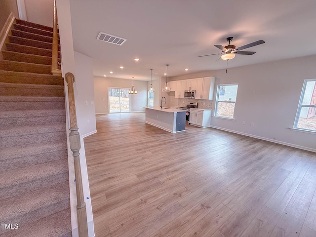 unfurnished living room featuring ceiling fan, light hardwood / wood-style floors, and sink