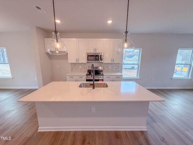 kitchen featuring decorative backsplash, stainless steel appliances, and a kitchen island with sink