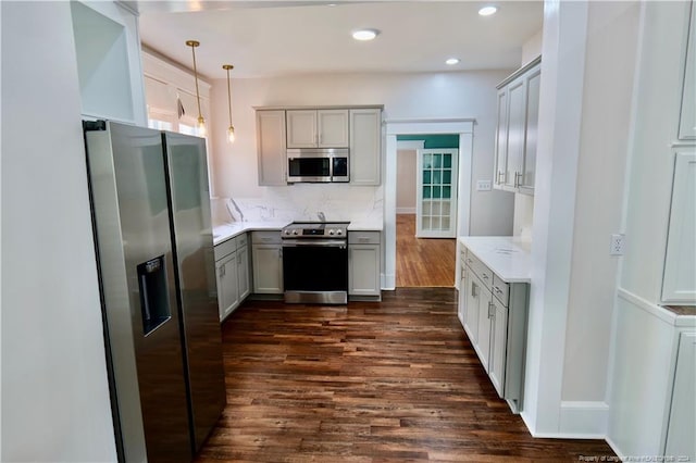 kitchen with backsplash, stainless steel appliances, dark wood-type flooring, pendant lighting, and gray cabinets